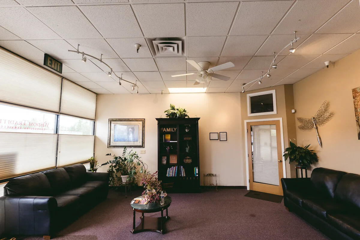 Empty Wisdom Traditions clinic waiting room with sofas, plants, and wall artwork.